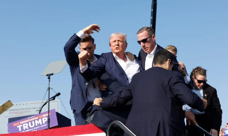 Görüntülerde, Trump’a yaklaşan bir kişinin aniden silahını çekerek ateş ettiği