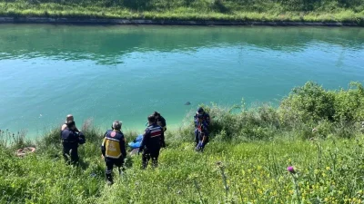 Adana’nın Yüreğir ilçesinde sulama kanalı kenarında yürüyen vatandaşlar suyun üzerinde