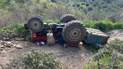 Manisa’nın Turgutlu ilçesinde eğimli arazide kontrolden çıkarak devrilen traktörün altında