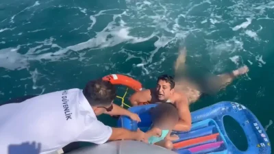 Aydın’ın Didim ilçesinde deniz yatağıyla suya bırakan küçük çocuk, rüzgarın